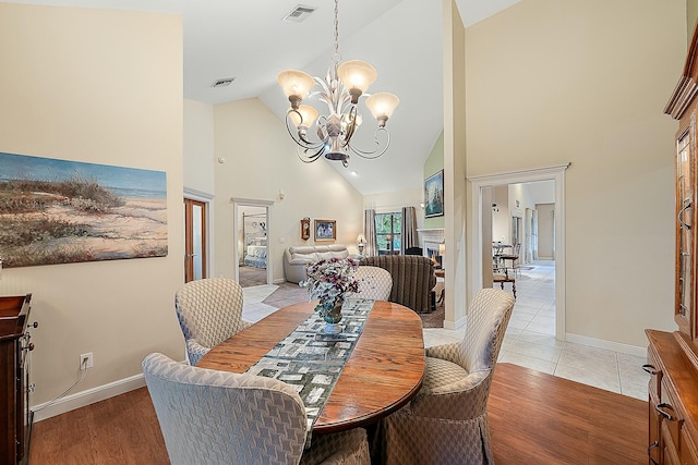 dining room featuring visible vents, baseboards, high vaulted ceiling, and an inviting chandelier
