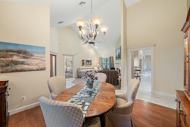 dining room featuring high vaulted ceiling, light hardwood / wood-style floors, and a chandelier