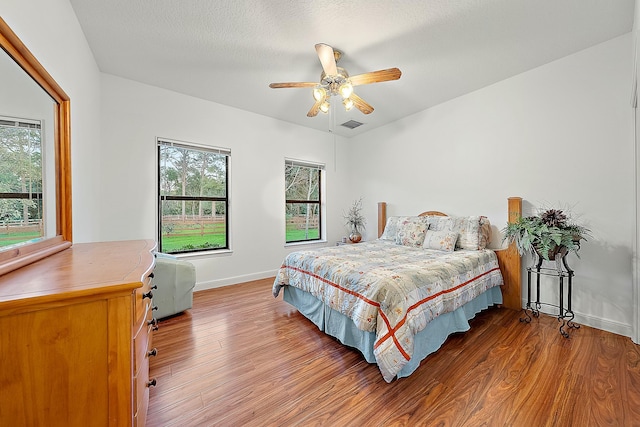 bedroom with ceiling fan, hardwood / wood-style floors, and a textured ceiling