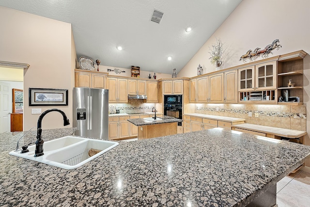 kitchen with black appliances, decorative backsplash, sink, high vaulted ceiling, and an island with sink