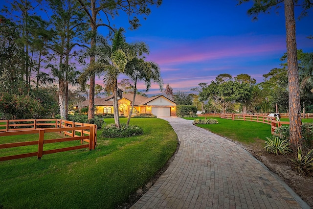 surrounding community with a lawn, decorative driveway, an attached garage, and fence