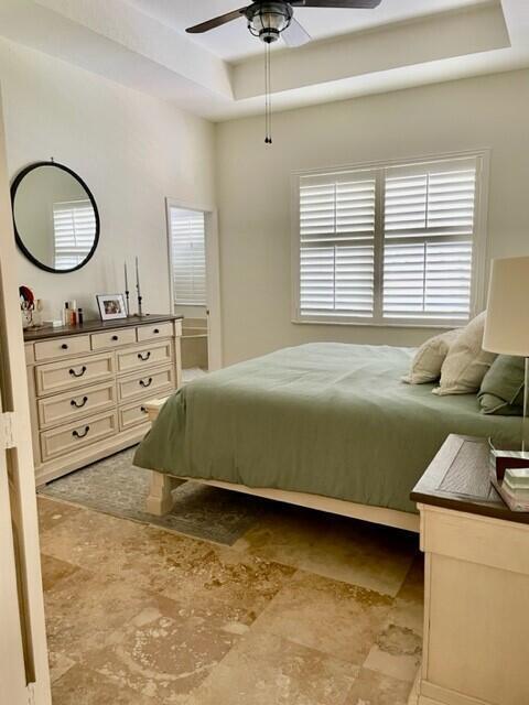 bedroom featuring ceiling fan and a raised ceiling