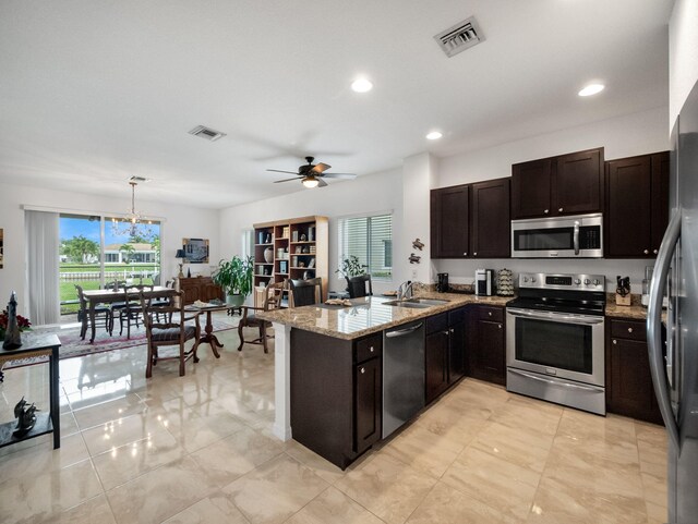 kitchen featuring appliances with stainless steel finishes, sink, hanging light fixtures, kitchen peninsula, and light stone counters