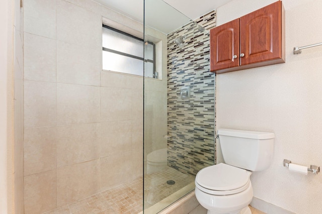 bathroom with a tile shower and toilet