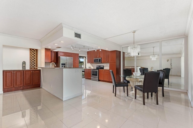 kitchen with appliances with stainless steel finishes, decorative light fixtures, an inviting chandelier, backsplash, and crown molding