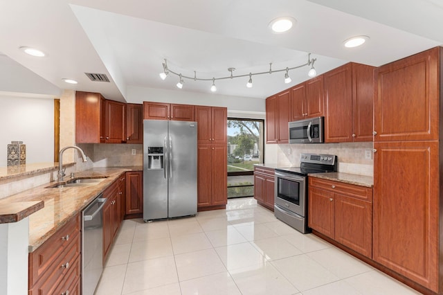 kitchen with sink, light stone counters, decorative backsplash, and appliances with stainless steel finishes