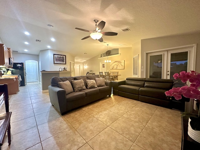 living room with a textured ceiling, french doors, vaulted ceiling, ceiling fan, and light tile patterned floors