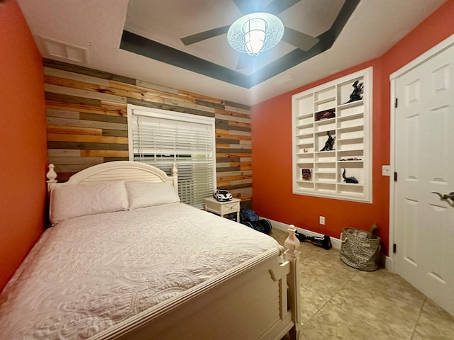 bedroom with ceiling fan, a tray ceiling, a closet, and wooden walls