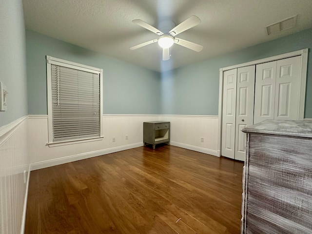 unfurnished bedroom with ceiling fan, a closet, and dark wood-type flooring