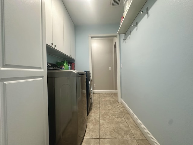 laundry area with cabinets, light tile patterned floors, and washing machine and clothes dryer