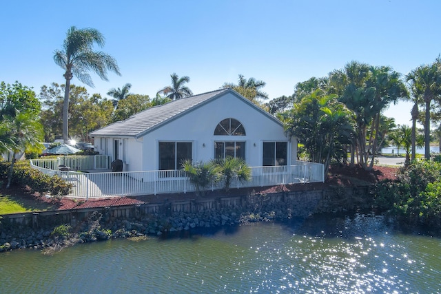 1401 SE Glencoe Ct, Port Saint Lucie, FL 34952 - rear view of house with a water view, fence, a tile roof, and stucco siding