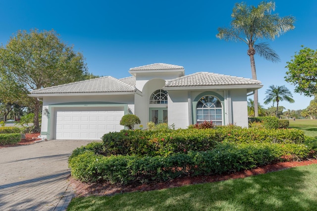 1401 SE Glencoe Ct, Port Saint Lucie, FL 34952 - mediterranean / spanish-style house featuring an attached garage, decorative driveway, stucco siding, and a tile roof