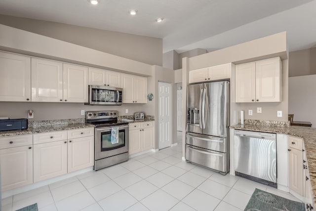 1401 SE Glencoe Ct, Port Saint Lucie, FL 34952 - kitchen featuring appliances with stainless steel finishes, vaulted ceiling, light stone counters, white cabinets, and light tile patterned flooring