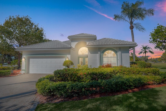 1401 SE Glencoe Ct, Port Saint Lucie, FL 34952 - mediterranean / spanish-style home with an attached garage, driveway, a tile roof, and stucco siding