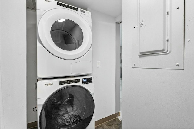 clothes washing area featuring parquet floors, electric panel, and stacked washer / dryer