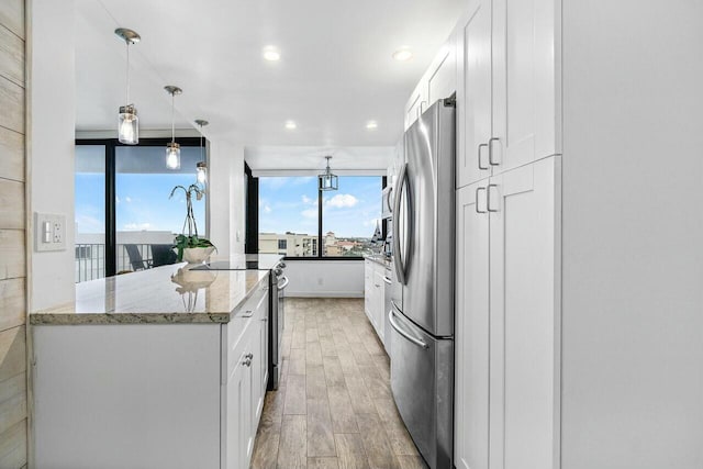 kitchen with hanging light fixtures, appliances with stainless steel finishes, light stone counters, and white cabinetry