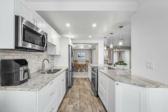 kitchen featuring backsplash, pendant lighting, sink, stainless steel appliances, and white cabinets