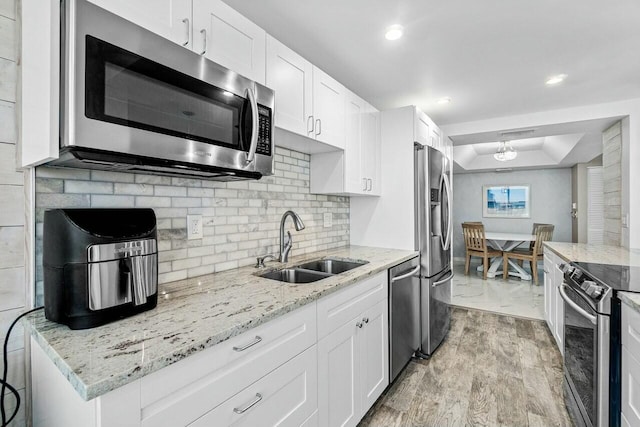 kitchen with stainless steel appliances, light hardwood / wood-style flooring, white cabinets, and sink