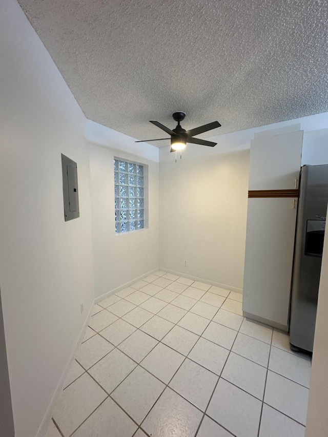 tiled empty room featuring electric panel, a textured ceiling, and ceiling fan