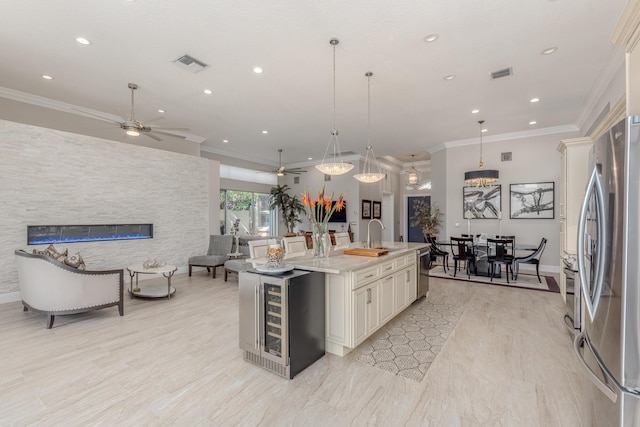 kitchen with pendant lighting, appliances with stainless steel finishes, a kitchen island with sink, and wine cooler