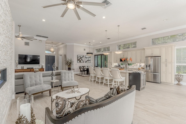 living room with crown molding, a stone fireplace, a wealth of natural light, and ceiling fan