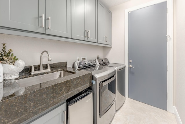 clothes washing area featuring cabinets, washer and clothes dryer, and sink