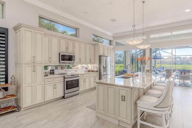 kitchen featuring pendant lighting, sink, stainless steel appliances, light stone countertops, and a center island with sink