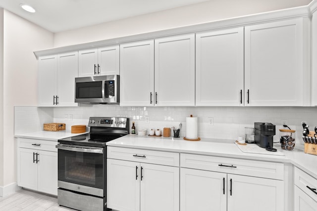 kitchen with white cabinets, backsplash, and appliances with stainless steel finishes