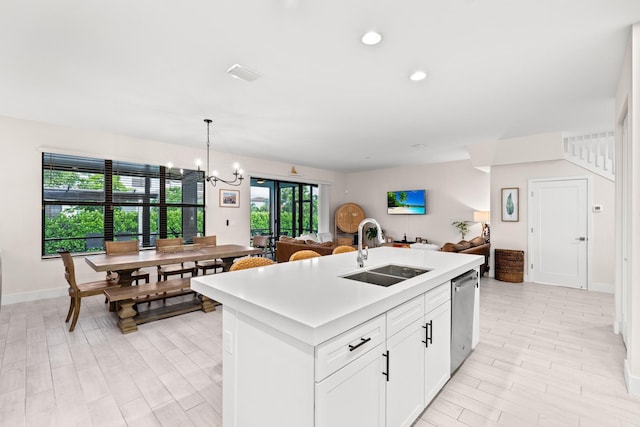 kitchen with white cabinetry, an island with sink, decorative light fixtures, stainless steel dishwasher, and sink