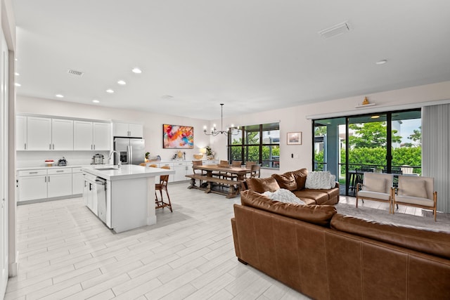 living room featuring sink, light wood-type flooring, and an inviting chandelier