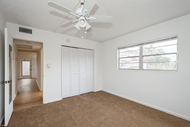 unfurnished bedroom with ceiling fan, carpet floors, a textured ceiling, and a closet