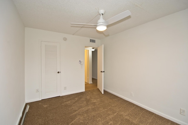 unfurnished bedroom with ceiling fan, dark carpet, and a textured ceiling