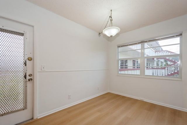 unfurnished room featuring light hardwood / wood-style floors and a textured ceiling