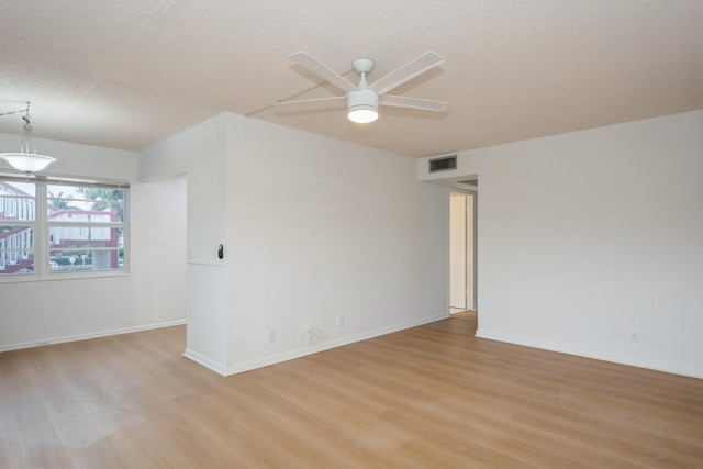 empty room featuring light wood-type flooring, a textured ceiling, and ceiling fan