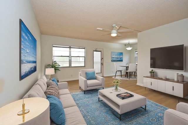 living room with hardwood / wood-style floors, a textured ceiling, and ceiling fan