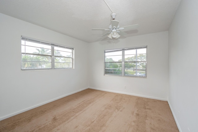 carpeted spare room featuring ceiling fan, a healthy amount of sunlight, and a textured ceiling