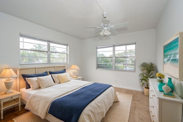 bedroom featuring ceiling fan, light colored carpet, and a textured ceiling