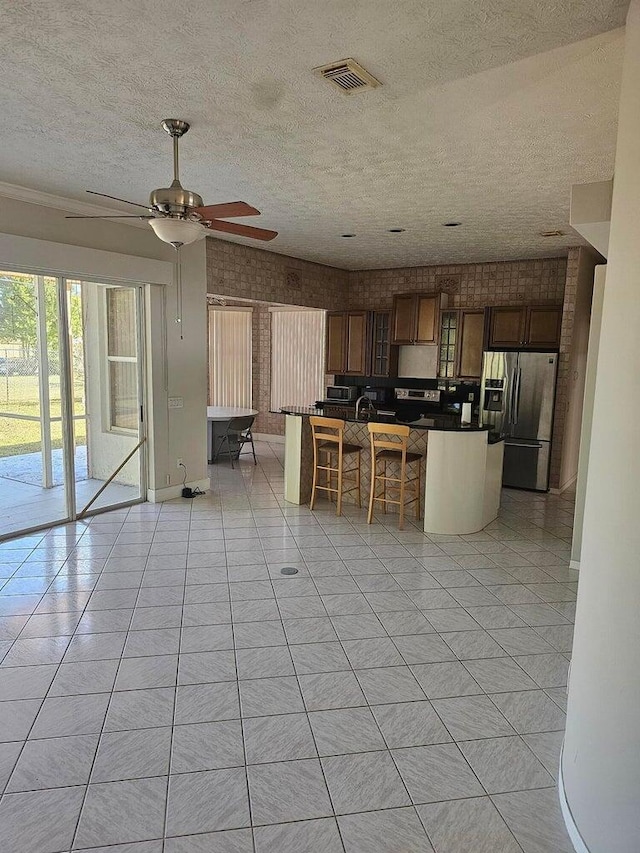 kitchen with light tile patterned flooring, ceiling fan, a textured ceiling, and stainless steel fridge with ice dispenser