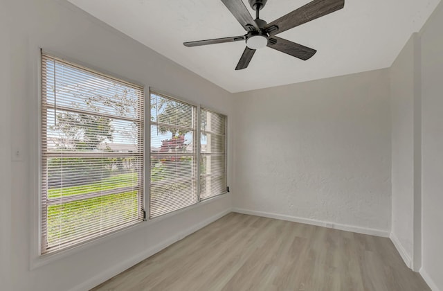 empty room with ceiling fan and light hardwood / wood-style flooring