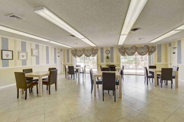 dining space featuring light tile patterned flooring, a healthy amount of sunlight, and a textured ceiling