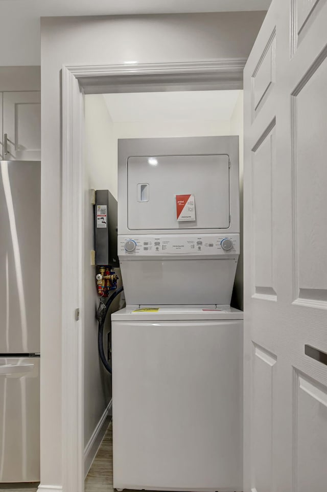 laundry area featuring hardwood / wood-style floors and stacked washing maching and dryer