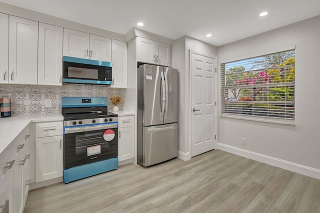 kitchen featuring white cabinetry, stainless steel appliances, light wood-type flooring, and backsplash