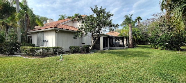 back of house with a sunroom and a lawn