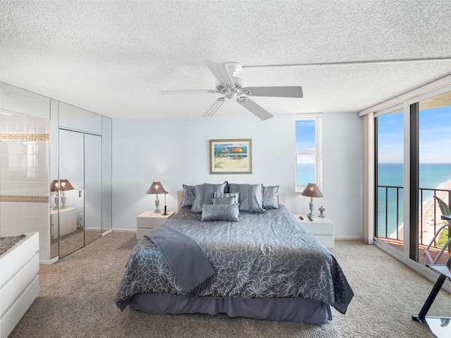 bedroom featuring a textured ceiling, carpet floors, a closet, a water view, and ceiling fan