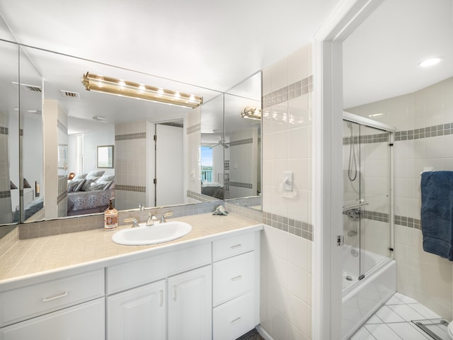 bathroom with tile walls, enclosed tub / shower combo, vanity, and tile patterned flooring