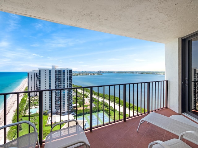 balcony with a water view and a view of the beach