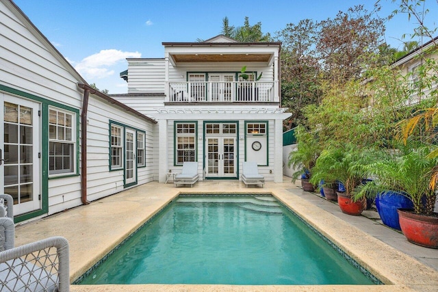 rear view of property featuring a balcony, french doors, and a patio