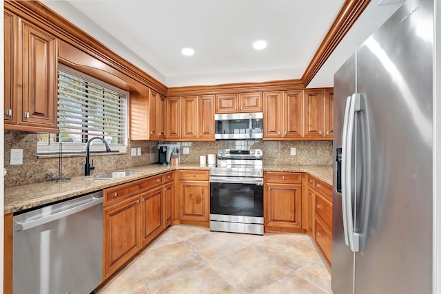 kitchen featuring sink, backsplash, light stone countertops, and appliances with stainless steel finishes