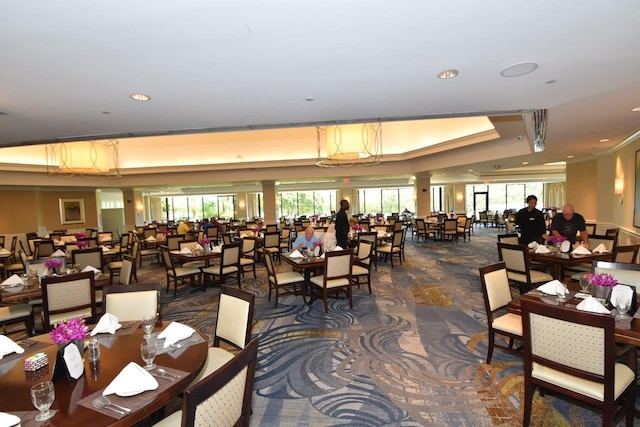 dining area featuring decorative columns, dark carpet, plenty of natural light, and a tray ceiling