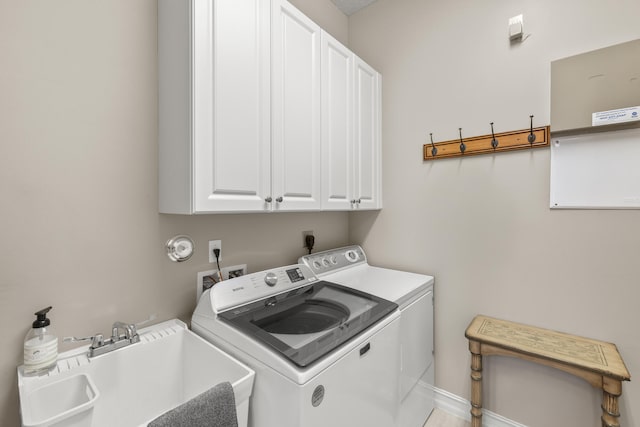 clothes washing area featuring separate washer and dryer, sink, and cabinets